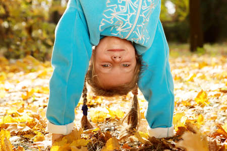 Portrait of a girl standing upside down in autumnal park