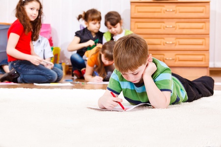 School aged boy lie on carpet drawingの写真素材