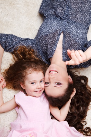 Mother and preschool girl lie on carpetの写真素材