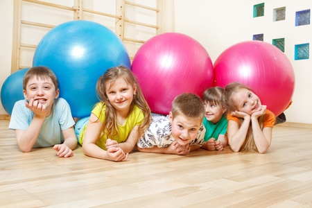 Five happy kids lie in gym with large ballsの写真素材