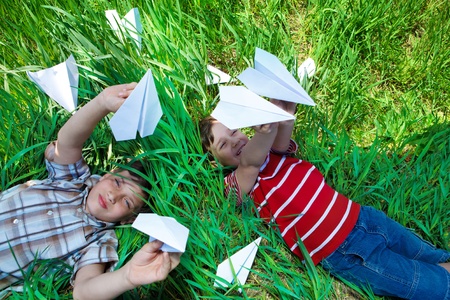 Kids lying on grass and playing with paper planesの写真素材