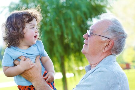 Great granddad holding  little curly baby in hands