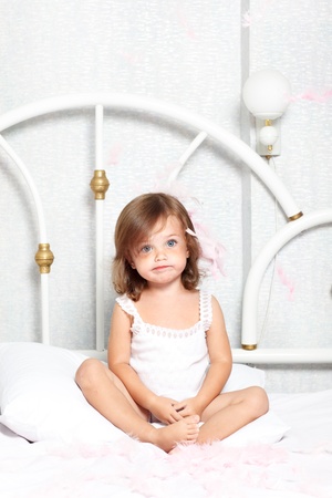 Puzzled little girl sit in bedの写真素材