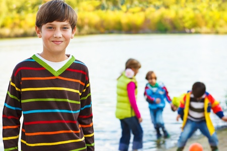 Smiling boy in front, and his friends playing with a ball in lakeの写真素材