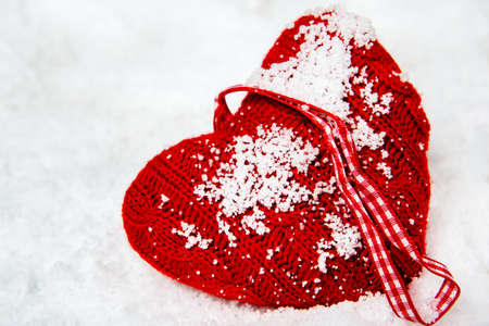 Red woolen heart left in snow
