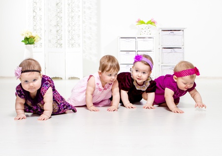 Group of four toddler girls in festive dresses crawlingの写真素材