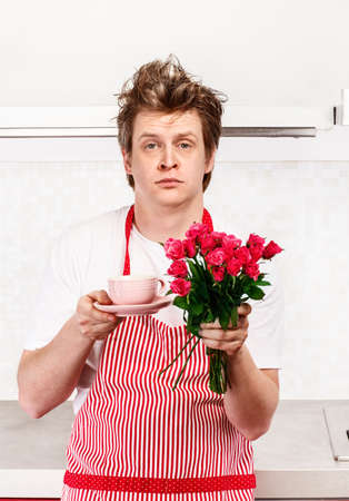 Sleepy unhappy man holding morning coffee and roses の写真素材