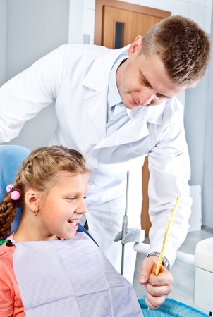 Dentist holding mirror for the girl to see her teethの写真素材