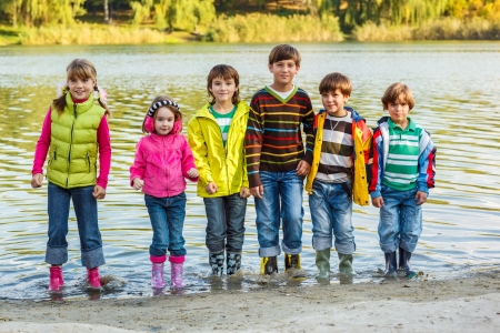 Cheerful children group standing in autumn riverの写真素材