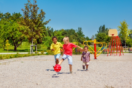 Excited kids running with a ball on the playgroundの写真素材