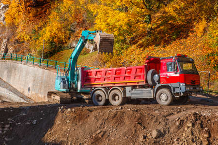 Truck and excavator working on the river bankの写真素材
