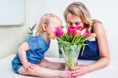 Mother and daughter sniffing tulip flowersの写真素材