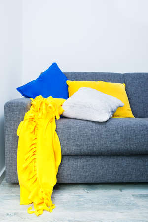 Part of modern sofa with blue, yellow and white cushions on it