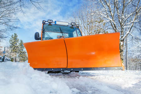 Orange snowplough with big blade cleaning the streets from snowの写真素材