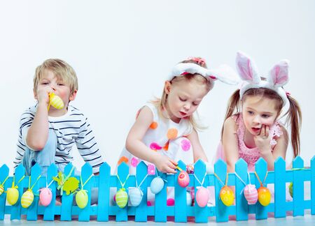 Preschool kids decorating fence with Easter eggsの写真素材