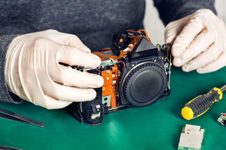 Close up of hands in latex gloves holding digital camera without front and back panelsの写真素材