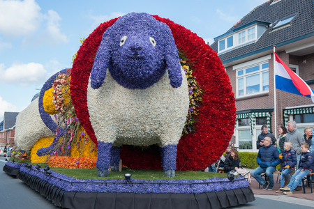 HILLEGOM, THE NETHERLANDS - APRIL 23, 2016: Moving platform with a huge frame made in a form of a sheep decorated with spring flowers. Taking part in the  traditional flowers parade "Bloemencorso". People often bring chairs to enjoy the parade.のeditorial素材