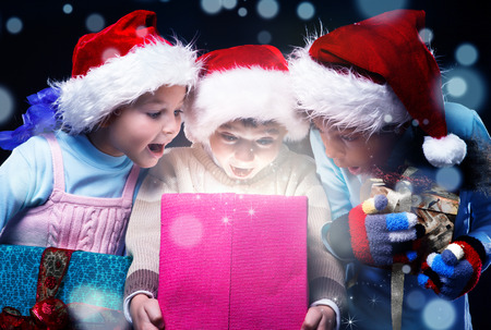 Surprised kids scream at opening a present box magic light insideの写真素材