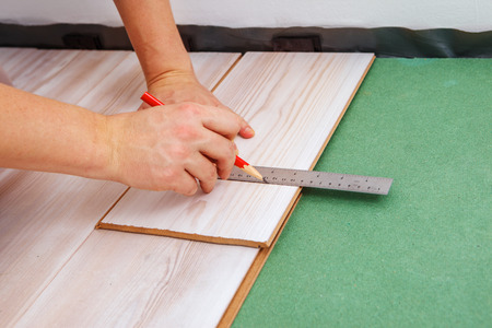 Hands of a contractor measuring the proper length of a laminate pieceの写真素材