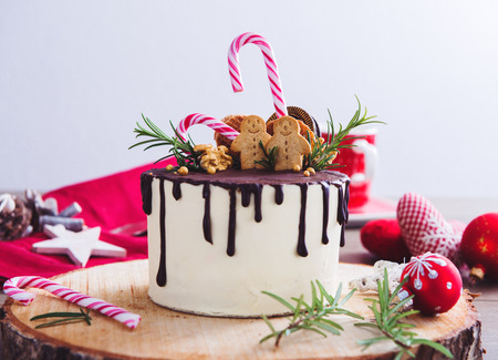 Homemade Christmas cake on a rustic wood stand and festive decorationの写真素材