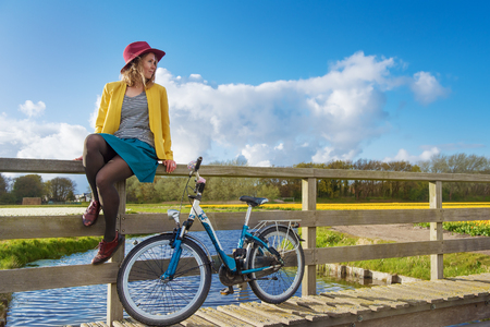 Smiling woman sitting on a wooden fence of the bridge over canal の写真素材