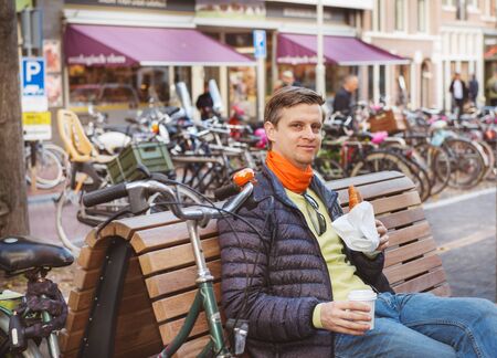 Smiling man sitting with a croissant and  take away coffeeの写真素材