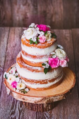 Homemade wedding naked cake  decorated with flowers on wooden cut standの写真素材