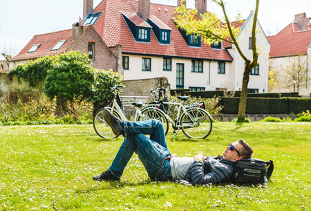 Tourist enjoying spring sunny day on green grass in a parkの写真素材