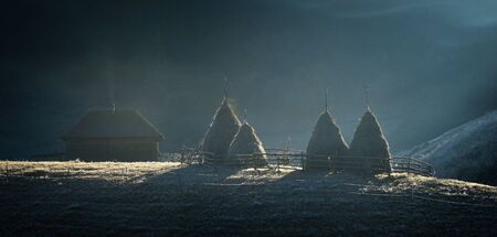 Frosty autumn morning in the village of shepherds Fundatura Ponorolui, Transilvania, Romania. Rural landscape with wooden houses and haystacksの写真素材