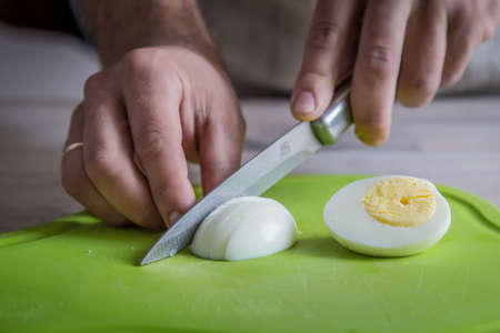 Cutting board with knife and hard boiled eggs on wooden table.の写真素材