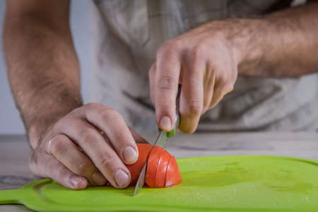 cutting tomato on green cutting boardの写真素材
