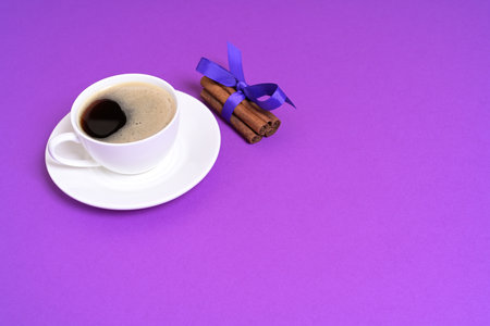 Cup of Black Coffee with Cinnamon Sticks on a Purple Backgroundの写真素材