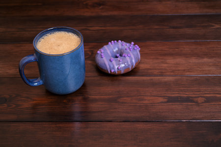 Blue Coffee Mug and Purple Donut on Wooden Tableの写真素材