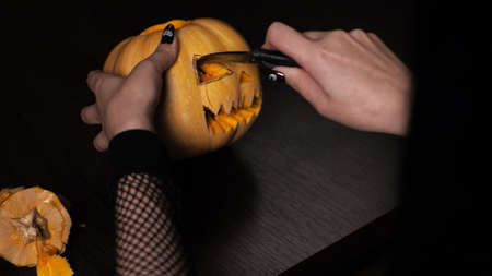 Young woman prepares a pumpkin for Halloween Cuts out the eyes Celebrationの写真素材