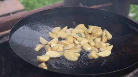 A man fries potatoes in the yard outside on the fire. Backyard Frying Pan Campingの写真素材