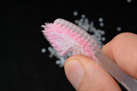 Toothbrush with pink bristles in hand on a black background