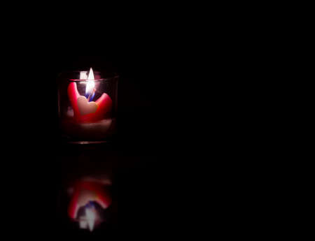 Heart shaped candles on black backgroundの写真素材