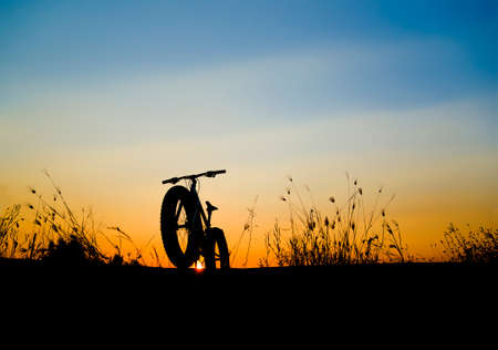 beautiful sunset sky and mountain bike silhouette , silhouette fat bikeの写真素材