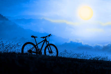 Silhouette Mountain bike on beautiful landscape, Silhouette Bicycle sunset on beautiful landscape mountain and foggy moonの写真素材