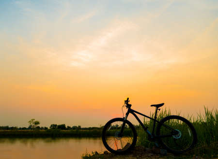 silhouette MTB, bicycle in grass at sunsetの写真素材