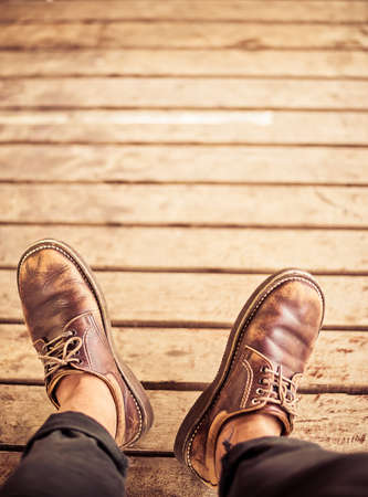 Top view of Male feet in old leather shoes on woodの写真素材