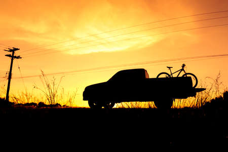 Silhouette Pickup truck with bicycle at sunset skyの写真素材