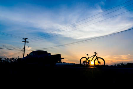 Silhouette Pickup truck with bicycle at sunset skyの写真素材