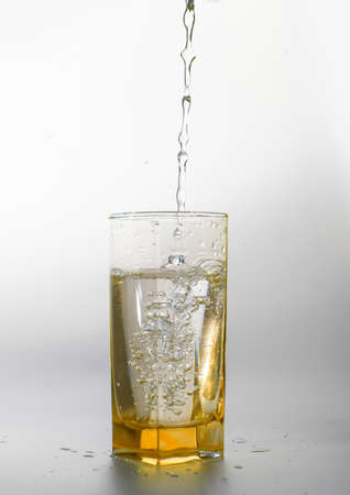 Pouring fresh drink water to yellow glassの写真素材