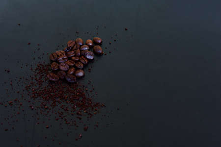 Coffee beans and ground powder on black background. Top view with copy space