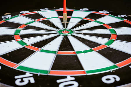 Close up Red dart arrow hitting on the center  dartboard, Marketing target success or the winner, on black backgroundの写真素材
