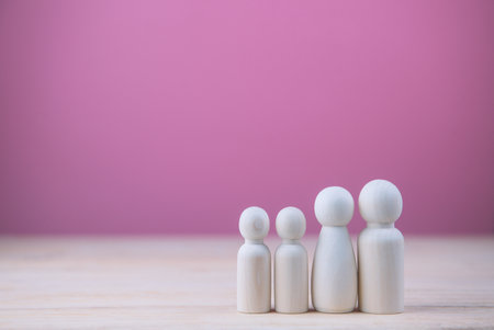 Wooden dolls human family with a home on pink background. family planning and coexistence happily concept.の写真素材