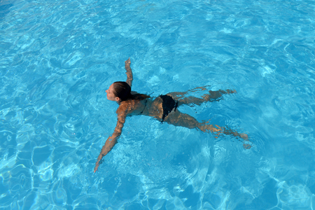 swimming young woman in blue water pool top viewの写真素材