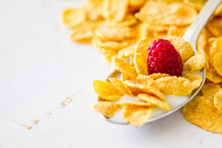 Cereal in spoon with raspberry, isolated on whiteの写真素材