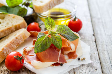 appetizer - ciabatta ham basil tomato, rustic wood backgroundの写真素材